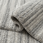 Close-up of a textured gray rug with a rolled edge.