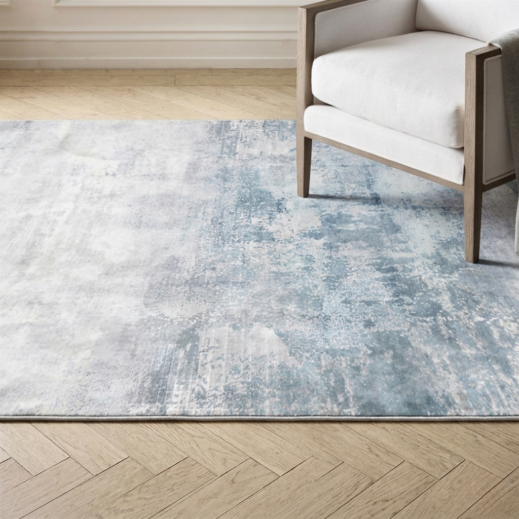 Blue and gray area rug on a wooden floor with a chair in the corner.