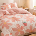 Bed with pink floral and strawberry patterned bedding in a bedroom setting.