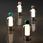 Set of four modern table lamps with colored tops on a reflective surface.