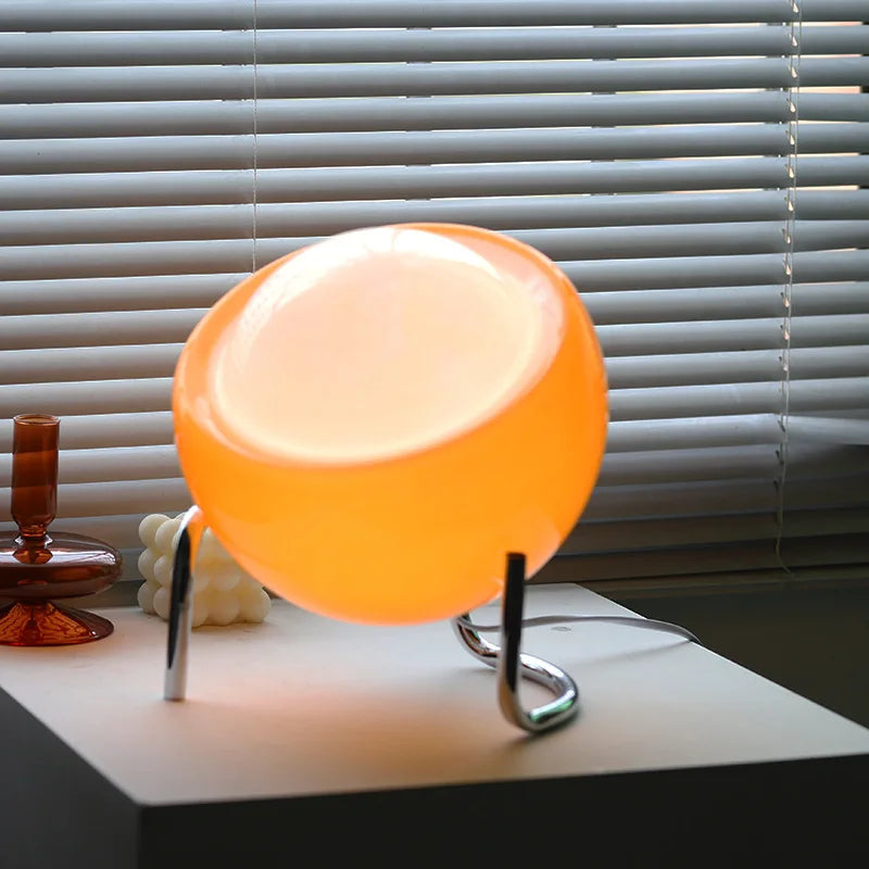 Orange lamp on a table with blinds in the background
