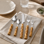 Bamboo handle flatware set arranged on a linen napkin in a bright dining setting.