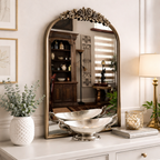 Decorative mirror with ornate frame on a white dresser with decorative items.