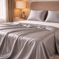 Gray satin blanket draped over a bed in a bedroom setting.