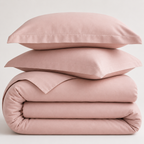 Stack of pink cotton bedding with two cotton pillows on a light gray background