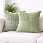 Two green textured pillows on a white couch with a plant in the background.