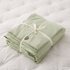 Folded green fabric with a button on a white mattress