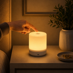 Hand touching a glowing night light on a bedside table with a plant and decorative items in the background.