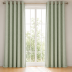 Pair of green curtains with metallic rings on a window with a view of trees.