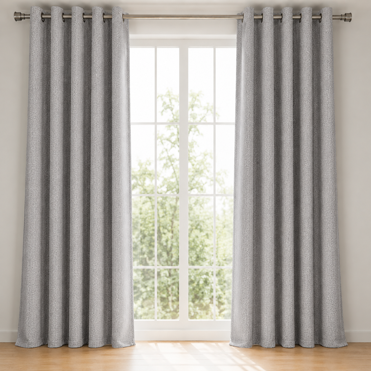 Gray curtains with grommets on a window with a view of greenery outside.