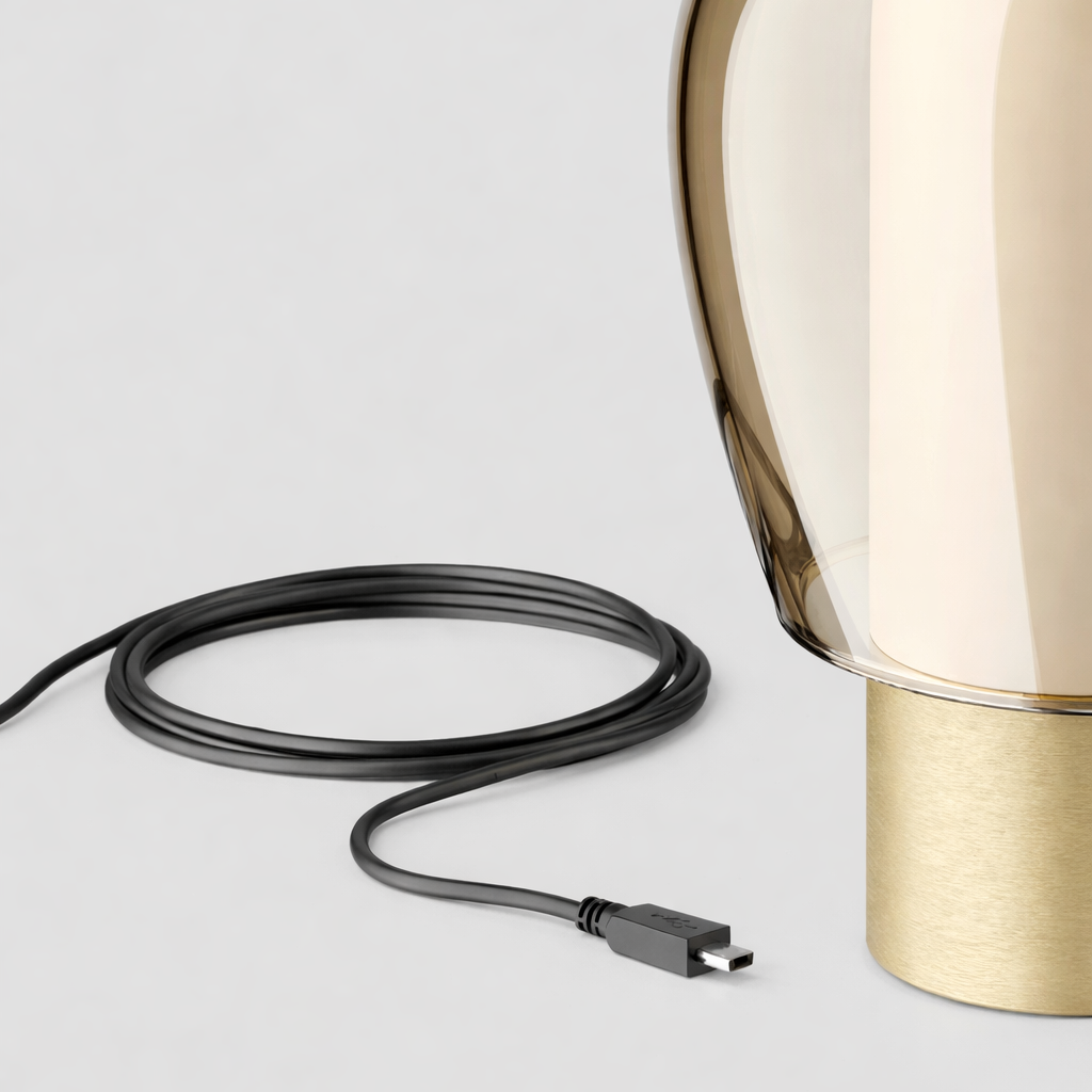Gold table lamp with USB cable on a light gray background