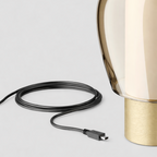 Gold table lamp with USB cable on a light gray background
