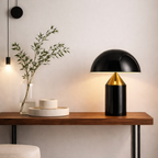 Modern black and gold table lamp on a wooden console table with decorative elements.