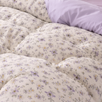 Floral patterned comforter on a bed with a pillow.