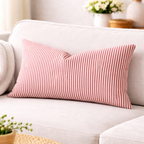 Red and white striped pillow on a white couch with a blurred background