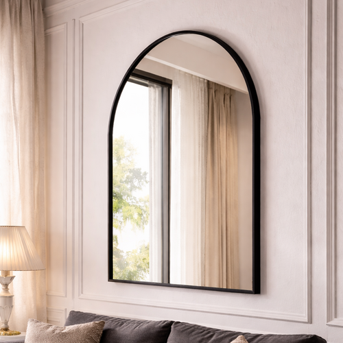 Arch-shaped mirror with black frame on a wall above a sofa