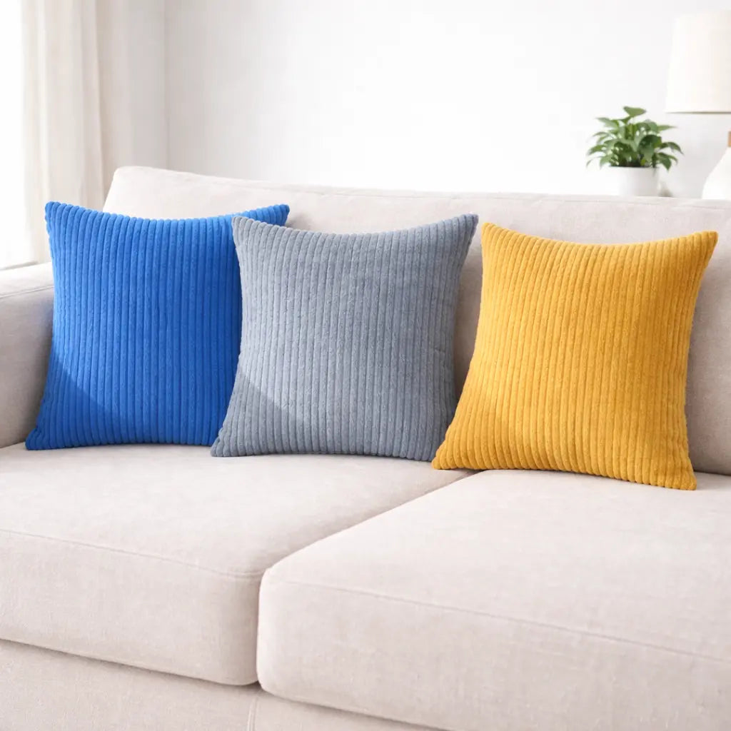 Three colorful pillows (blue, gray, yellow) on a light-colored sofa.