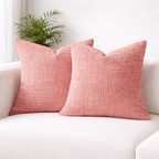 Two pink textured pillows on a white couch with a plant in the background.