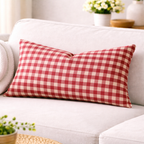 Red and white checkered pillow on a white sofa with a blurred background