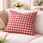Red and white checkered pillow on a beige sofa with a blurred background