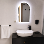 Bathroom vanity with white sink, black cabinet, and illuminated mirror.
