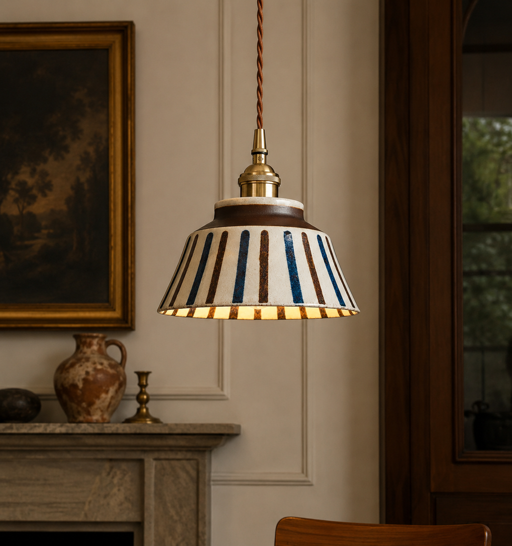 Striped pendant light hanging in a room with a painting and vase on a mantelpiece.