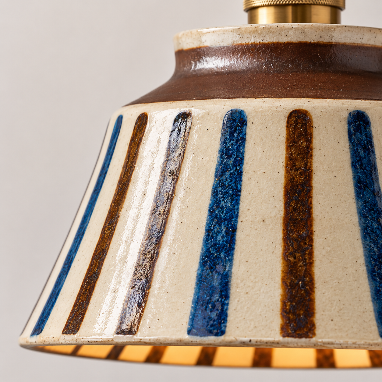 Close-up of a ceramic lampshade with blue and brown stripes on a gray background