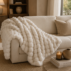 White textured blanket draped over a beige sofa in a cozy living room.