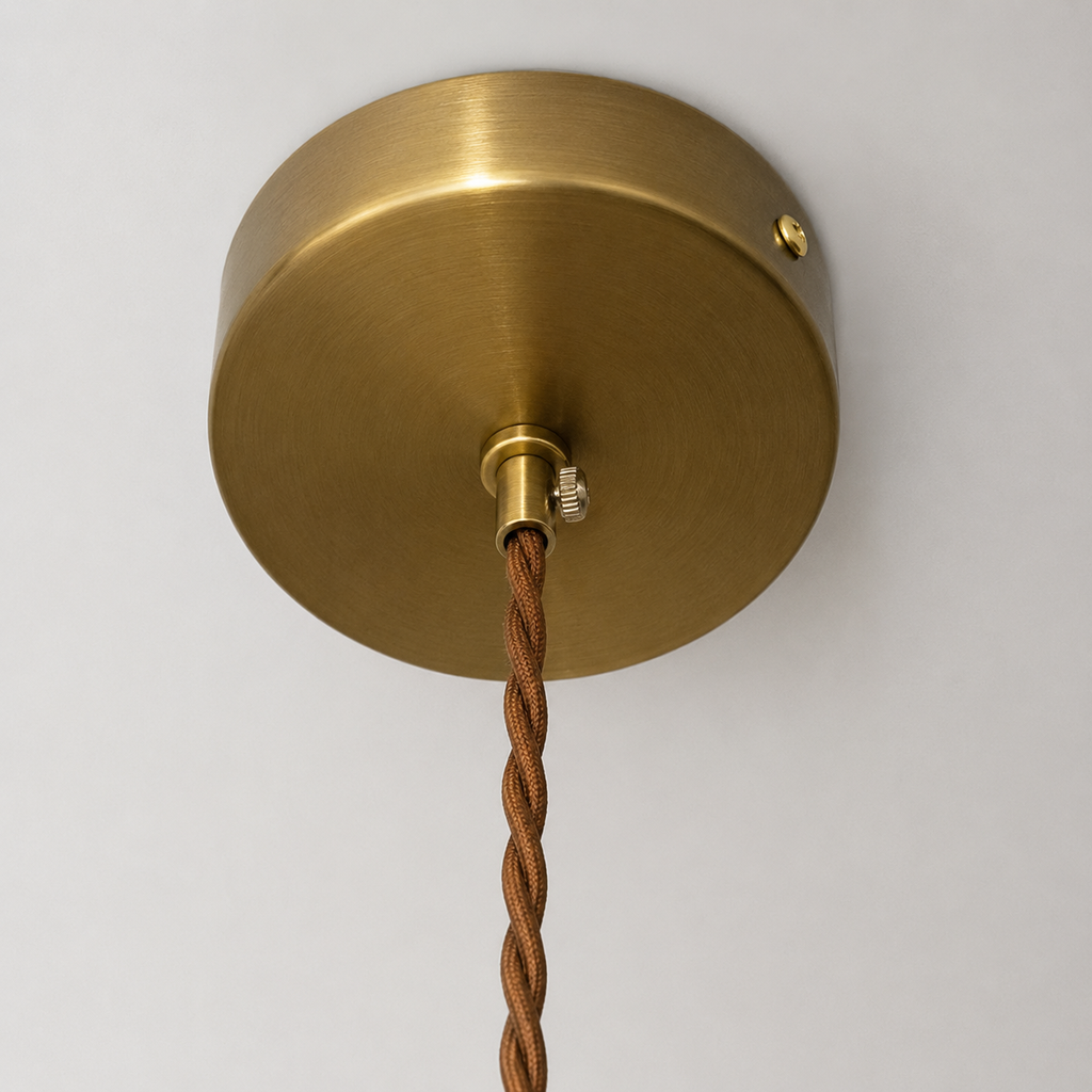 Brass ceiling rose with brown textured cable on a white background