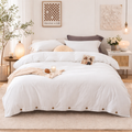 Neatly made bed with white bedding in a bedroom setting.