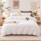 Neatly made bed with white bedding in a bedroom setting.