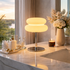 Modern table lamp on a marble surface with decorative items and a scenic view.