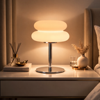 Modern table lamp on a nightstand with decorative items in a cozy bedroom setting.