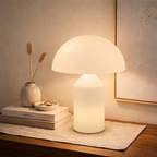 Table lamp on a wooden surface with books and decorative items in a warm setting